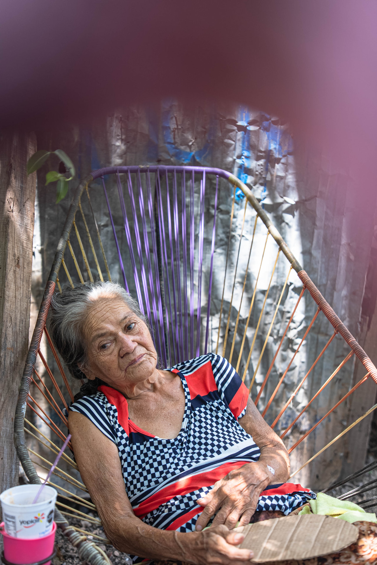 Older woman seated in a colorful woven chair