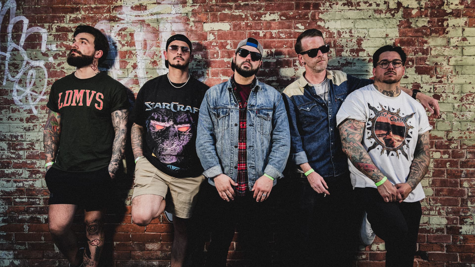 Five members of St. Wade Vincent standing against a weathered brick wall