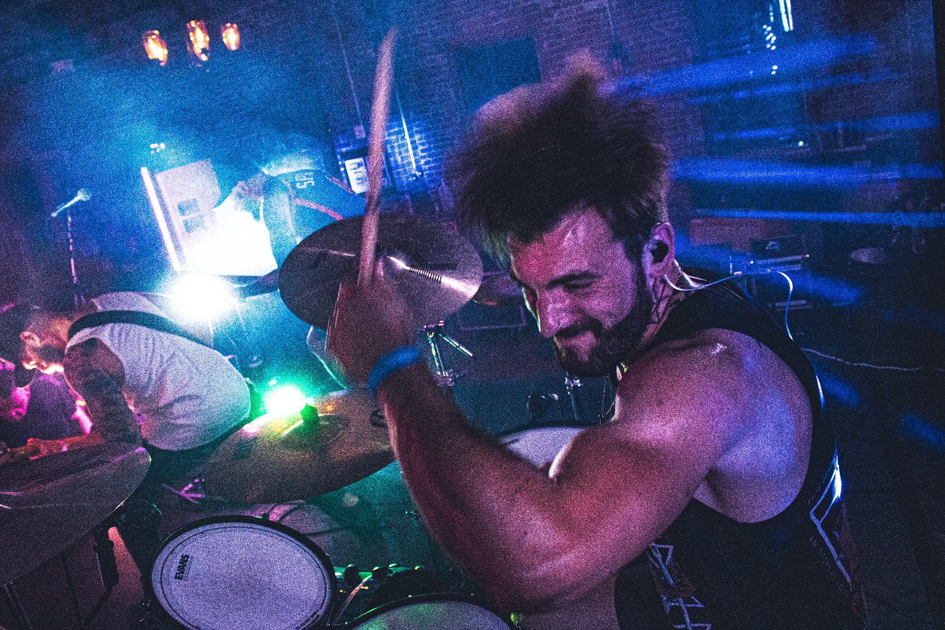 Drummer performing live under blue and purple stage lighting