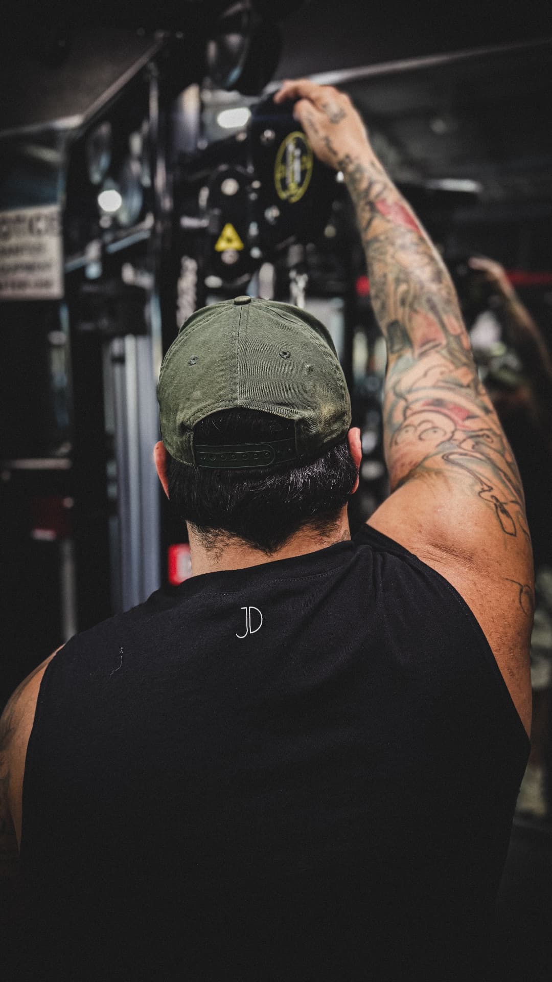 Rear view of Joey reaching upward, the small JD mark high on the back of the shirt