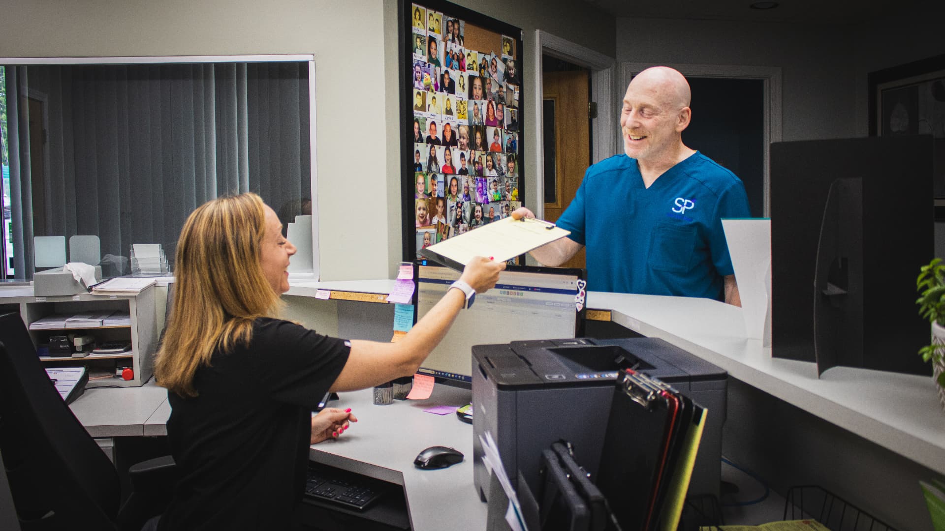 Stony Point Dental team member handing a clipboard across the front desk