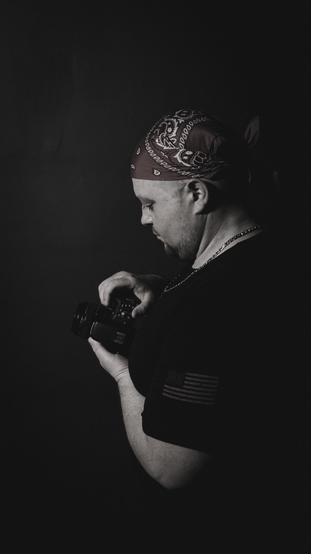 Joey DiCara looking down at his camera in a dark cinematic portrait.
