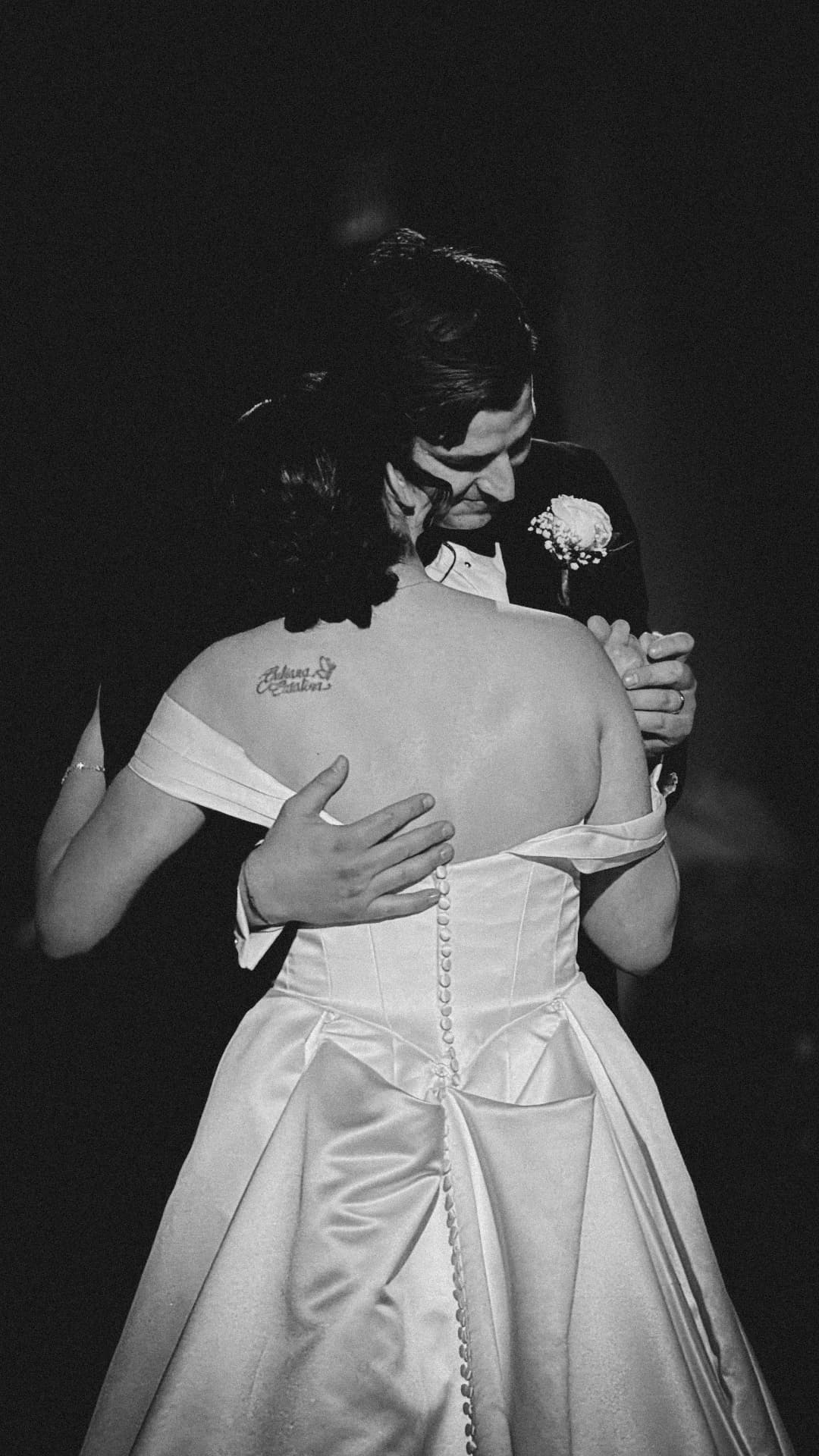 Black and white wedding dance viewed from behind the bride as the couple embraces