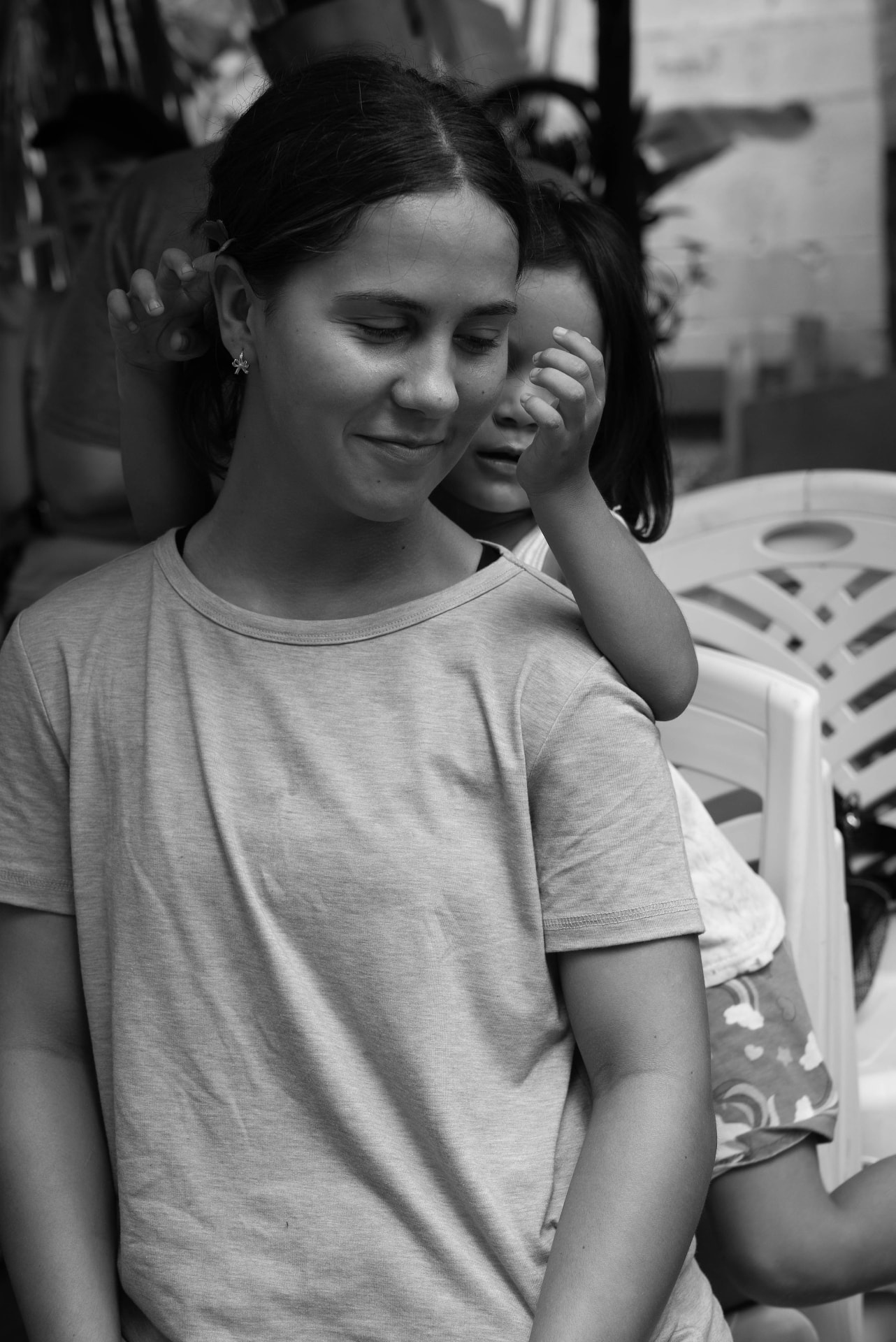 Black and white photograph of two girls, one behind the other touching her hair