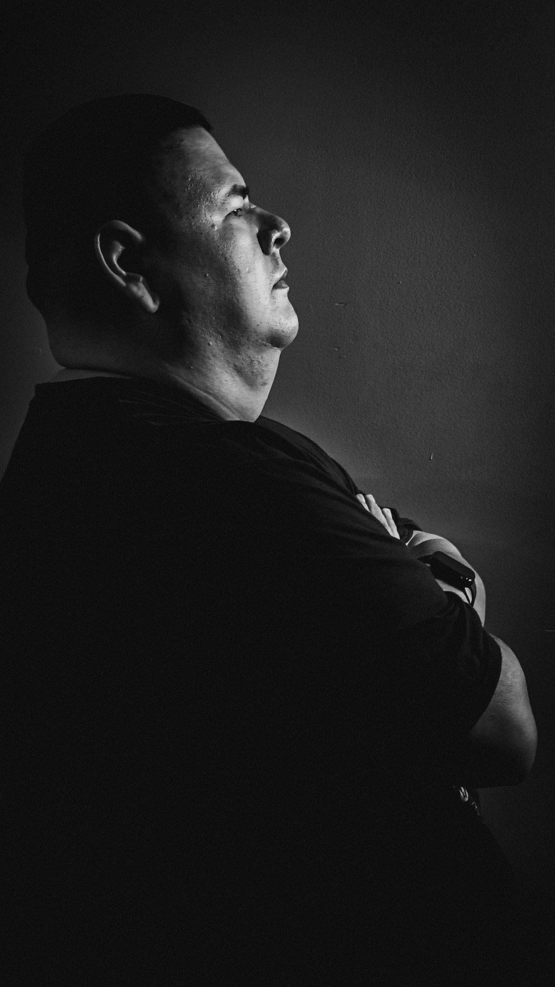 Black-and-white profile portrait of a man facing right, emerging from deep shadow